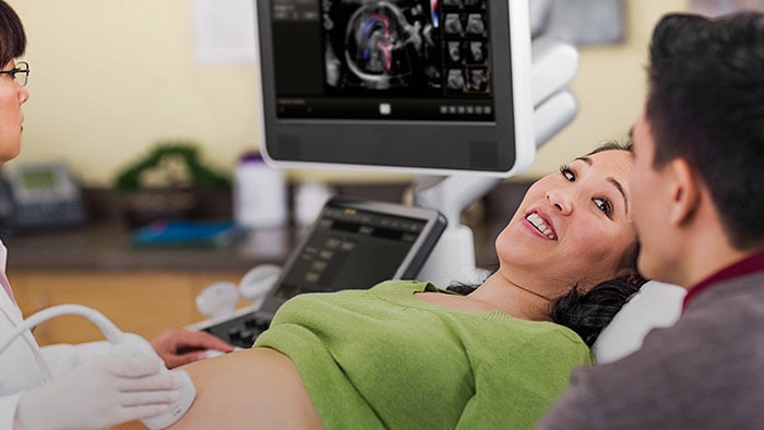 A pregnant woman having ultrasound with her partner sitting next to her
